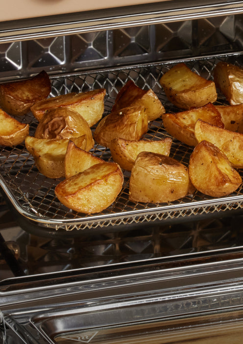 Golden-brown potato wedges roasting on a wire rack inside an oven.