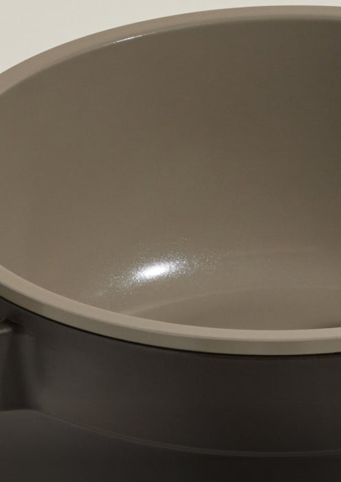 A close-up view of a round, taupe-colored ceramic bowl with a smooth, glossy interior surface.