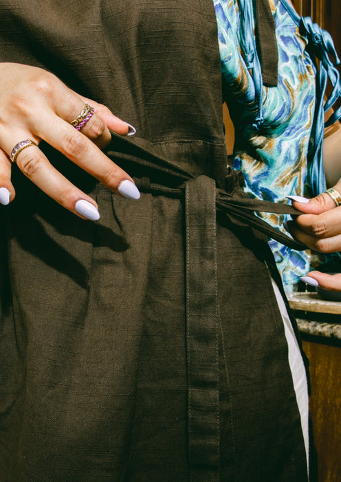 A chef ties a black Hosting Apron