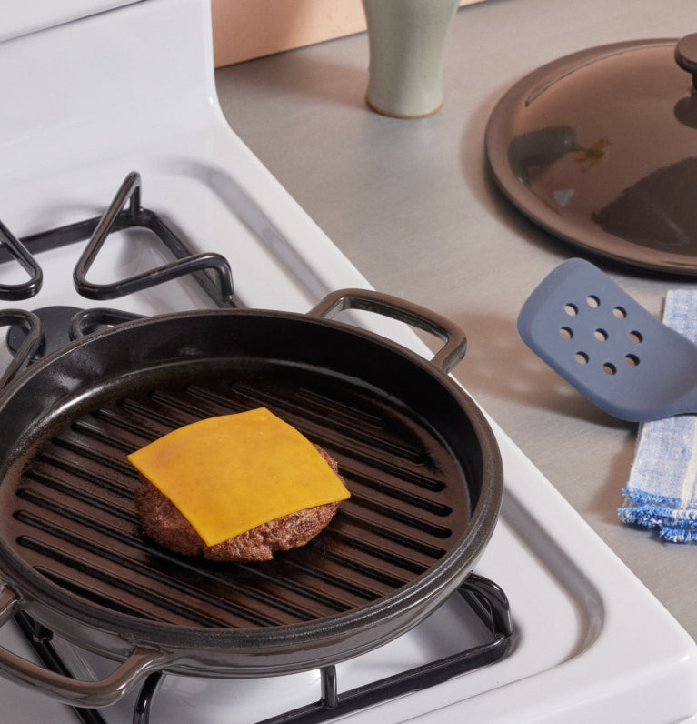 black cast iron hot grill with cheeseburger on stovetop