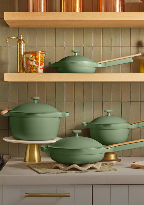 Green cookware set on a kitchen counter with copper accents