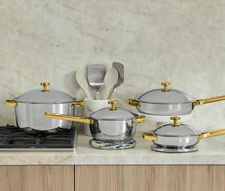 Set of silver cookware with gold handles on a kitchen counter.