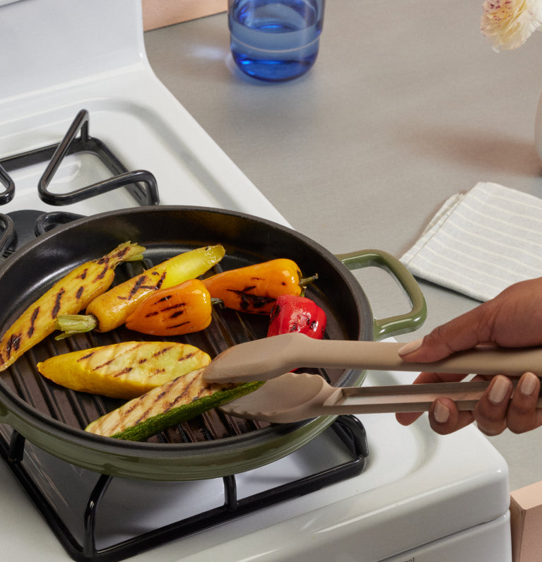 green cast iron hot grill on stovetop with vegetables