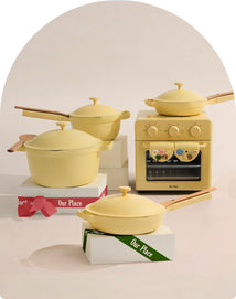 Set of yellow cookware including pots and a small oven on a neutral background