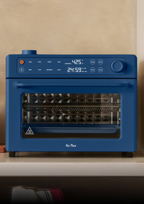 Blue toaster oven on a countertop with a beige wall background