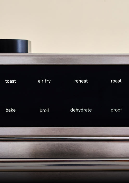 Stainless steel kitchen appliance with control panel buttons labeled 'toast', 'air fry', 'reheat', 'roast', 'bake', 'broil', 'dehydrate', and 'proof'.