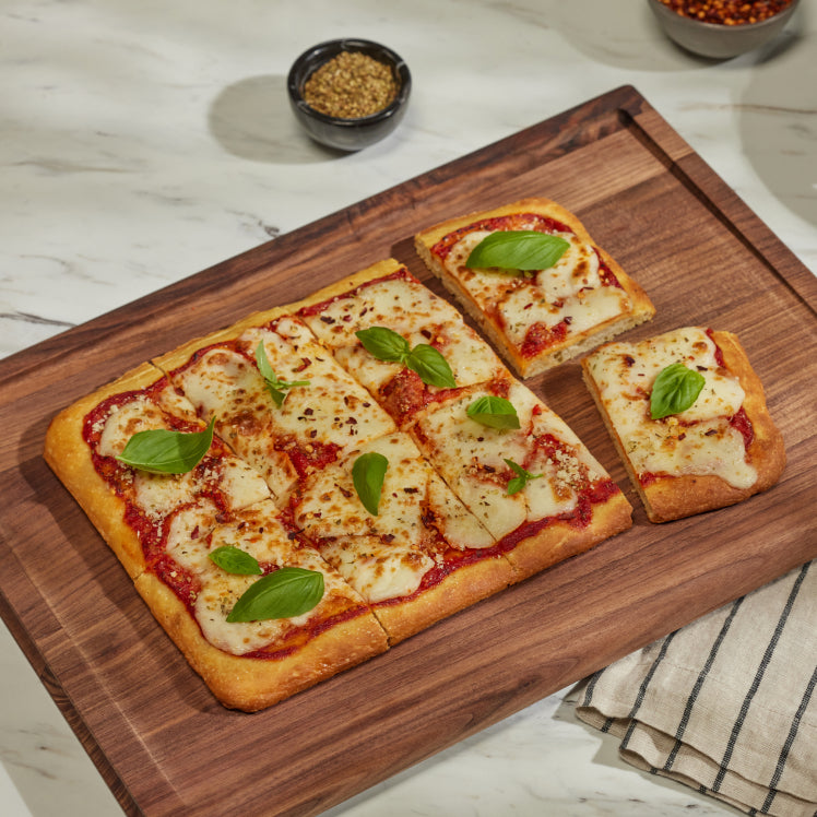 cooked pizza set on walnut cutting board