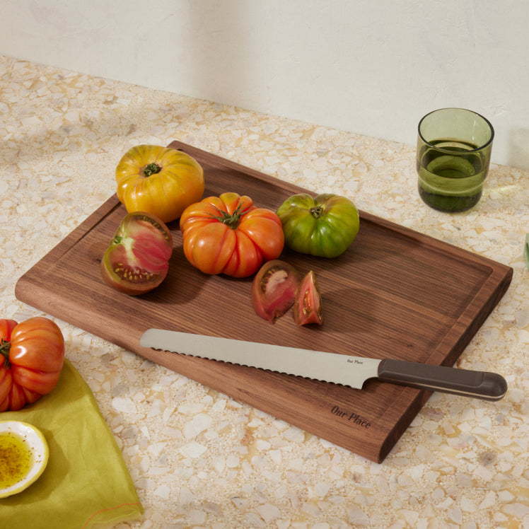 cutting tomatoes with serrated slicing knife on walnut cutting board