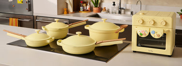 Set of yellow cookware including pots and a small oven on a kitchen counter.