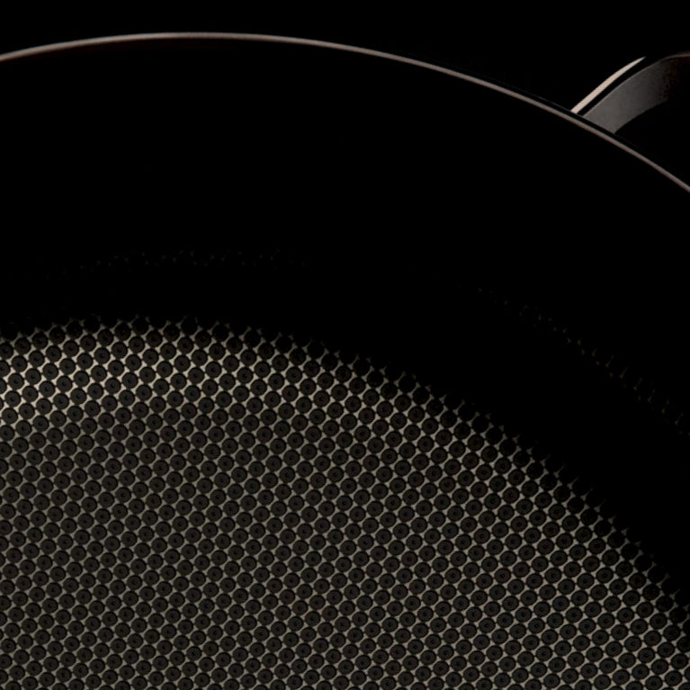 Close-up of a nonstick frying pan with a hexagonal textured surface, shown partially against a dark background.