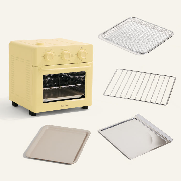 Yellow toaster oven with accessories including a baking tray, rack, and lid on a white background