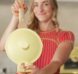 Woman holding a yellow pan with a wooden handle