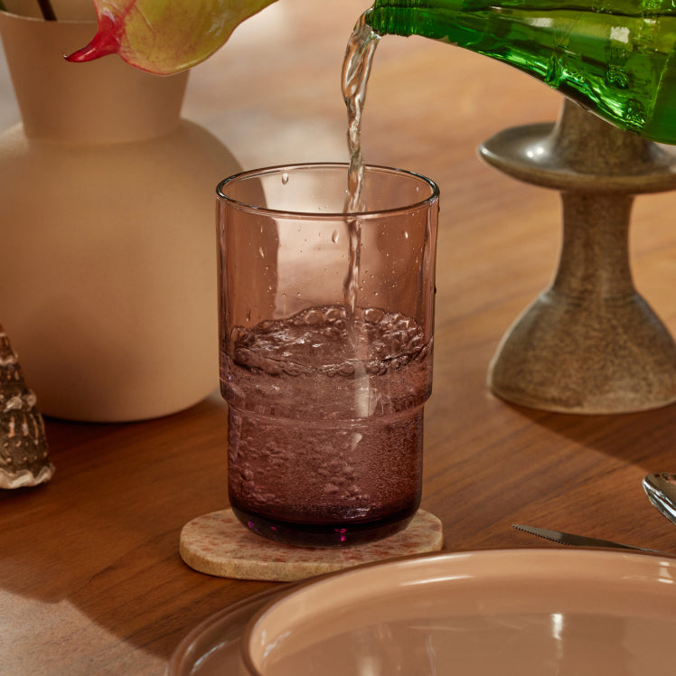 Pouring sparkling water into a pink Tall Night + Day Glass