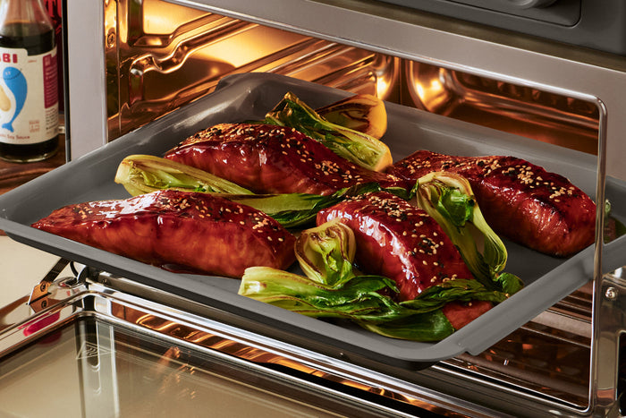 Glazed salmon and bok choy on a baking sheet
