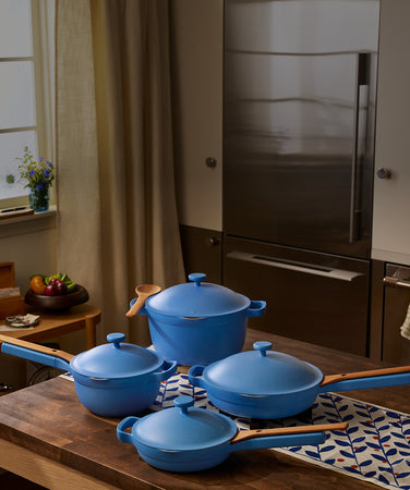 Set of blue cookware on a wooden table with a kitchen background