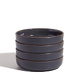 A stack of four dark gray ceramic bowls with a matte finish, set against a plain white background.
