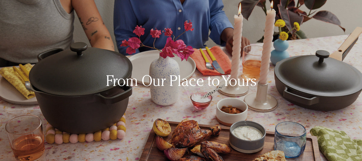 Translation missing: en.Two people sit at a table set with food, drinks, candles, flowers, and two black pots, with the text From Our Place to Yours overlaid