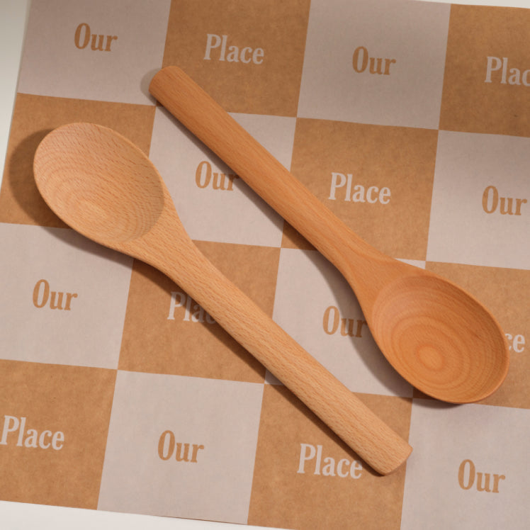 two notched beechwood spoons on an our place branded backdrop