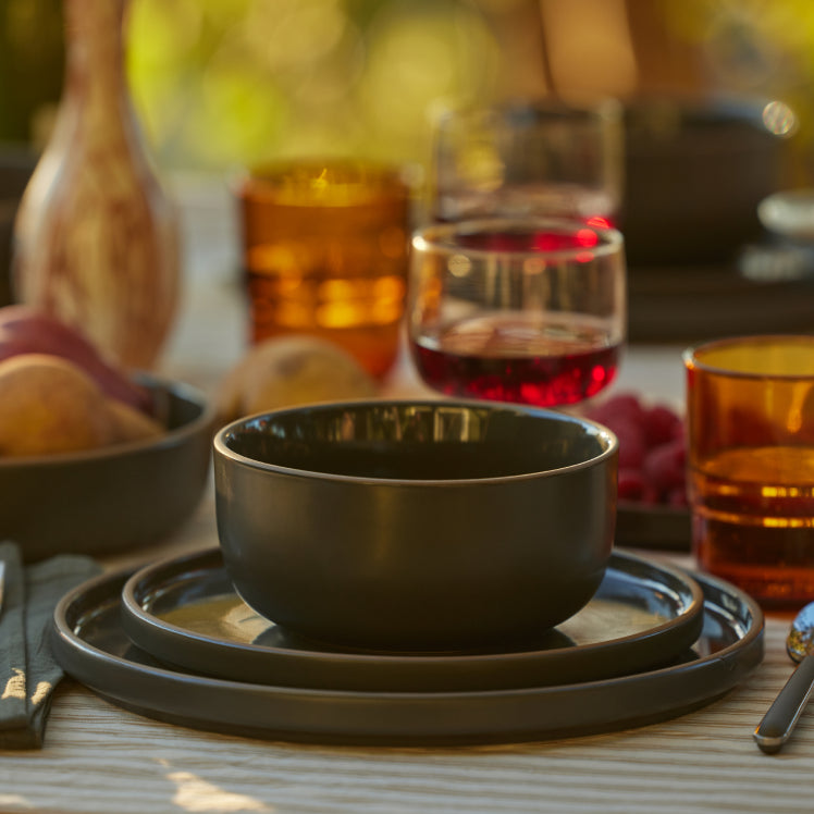 black soup bowl, salad plate and dinner plate set on table