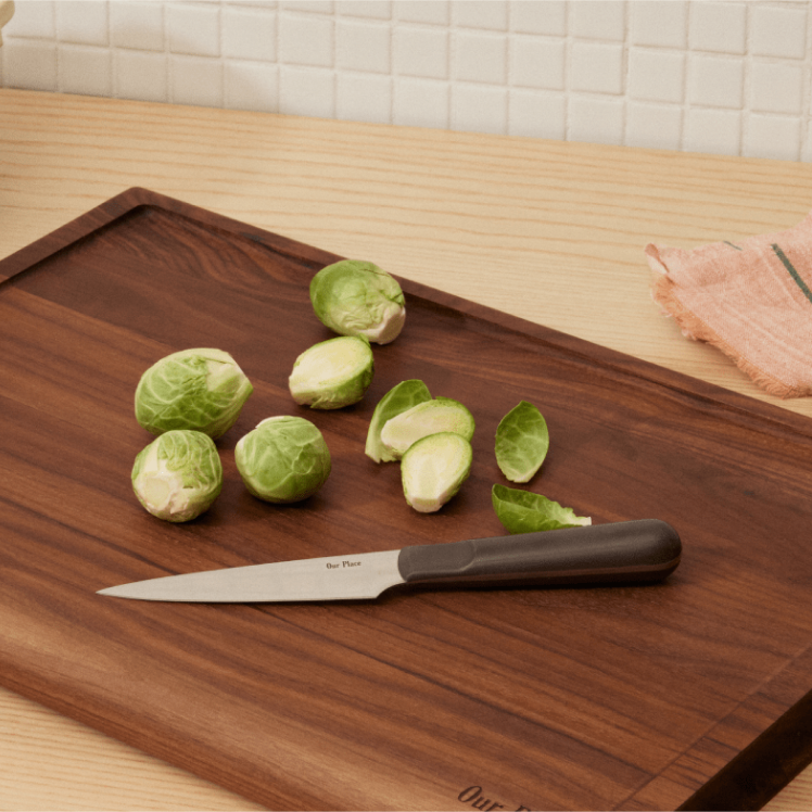 Black Precise Paring Knife on top of the Walnut Cutting Board with a Brussels sprouts