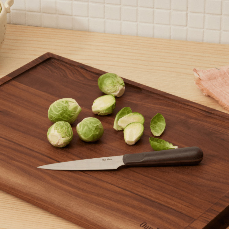 black precise paring knife on walnut cutting board with Brussels sprout