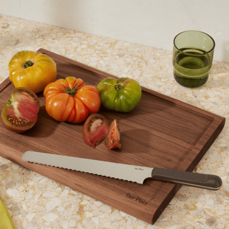 Black Serrated Slicing Knife on top of the Walnut Cutting Board with tomatoes