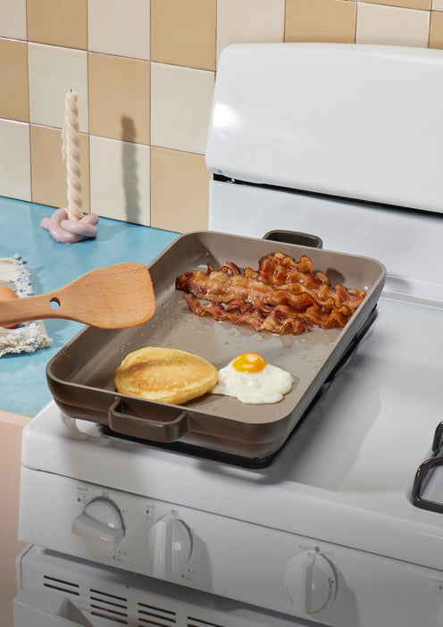 black griddle pan on stovetop with bacon and egg