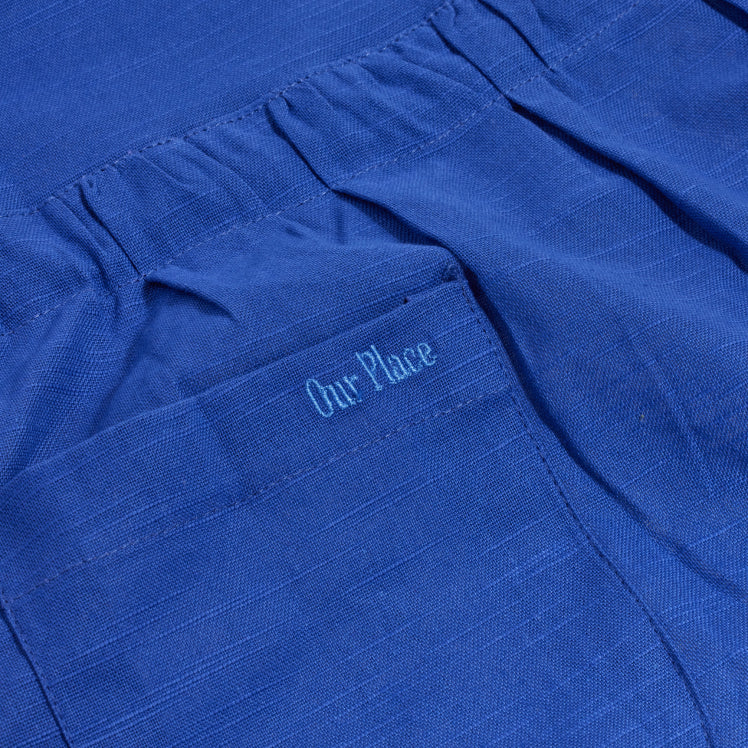 Our Place logo embroidered on the pocket of a blue Hosting Apron