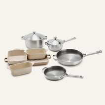 Titanium Pro Cookware + Bakeware Set (2.0) featuring stainless steel cookware alongside cream-colored ceramic bakeware, including a rectangular tray and loaf pans.