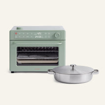 The Wonder Oven® Pro, featuring a green finish and digital display, is displayed alongside the matching round stainless steel braiser with handles and a lid—offered together as the Wonder Oven® Pro + Braiser Set.
