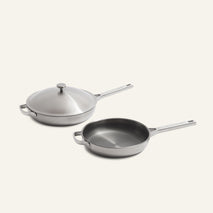 Titanium Pro Always Pan Duo (2.0) featuring two brushed stainless steel pans with long handles and helper handles, one with a matching lid.