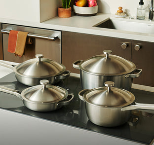 Set of stainless steel cookware on a kitchen stove with a modern kitchen background.