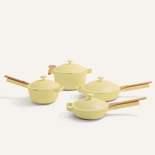 The Cookware Set features four pale yellow pieces with lids and light wooden handles, similar to the Always Pan and Perfect Pot, shown on a plain, light background.