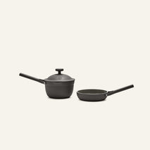 The Tiny Cookware Duo, featuring a black saucepan with lid and a matching frying pan, is displayed side by side on a light background.