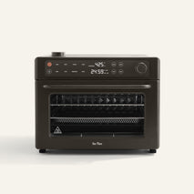 A black countertop oven with digital display showing 425°F and 24:59, two dials, buttons, and three internal racks, set against a plain light background.