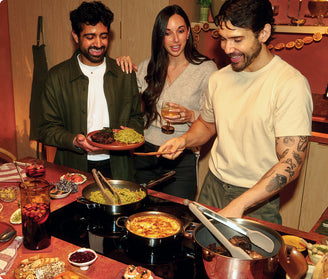 Three people around a table with food and drinks in a casual setting