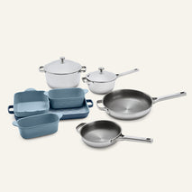 Titanium Pro Cookware + Bakeware Set (2.0) featuring two stainless steel pots with lids, two stainless steel frying pans, and four blue ceramic bakeware dishes stacked on a rectangular tray.