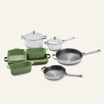 Titanium Pro Cookware + Bakeware Set (2.0) featuring two stainless steel pots with lids, two stainless steel skillets, and three green ceramic bakeware dishes on a small, checkered tray.