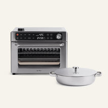 The Wonder Oven® Pro + Braiser Set, featuring a stainless steel countertop oven with digital controls and a round, lidded titanium braiser pan with handles, is set against a plain light background.