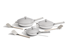A set of three gray nonstick pans with lids and three matching spatulas, arranged on a white background.