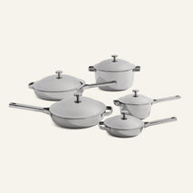 The Titanium Pro Cookware Set+ includes five stainless steel pieces—two saucepans, a stockpot, sauté pan, and skillet—each with a matching lid, all stylishly displayed on a light surface.