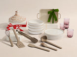Set of ceramic dishes, glasses, and wooden utensils on a beige background