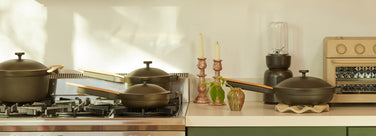 black perfect pot, mini always pan and mini perfect pot on stove. Black splendor blender, always pan and beige wonder oven on counter