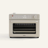 A beige countertop oven with digital display, control knobs, and a glass door showing racks and a pan inside.
