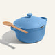 A blue Ceramic Nonstick Perfect Pot 6 L with a matching lid and a wooden spoon resting on top, set against a plain light background.