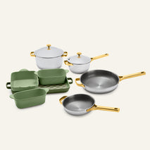 Titanium Pro Cookware + Bakeware Set (2.0) featuring stainless steel cookware with gold-toned handles and lids, sage green ceramic bakeware, and a matching checkered tray.