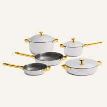 The Titanium Pro Cookware Set + Braiser, featuring five elegant white pots and pans with matching gold handles and lids, is displayed on a plain light background—perfectly combining refined style with the lasting durability of quality stainless steel cookware.