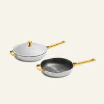 Titanium Pro Always Pan Duo (2.0) featuring two light gray titanium pans with metallic gold handles, one covered with a matching lid.