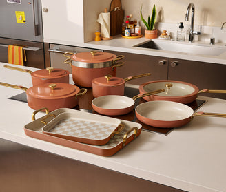 Ceramic cookware set on a kitchen counter with a neutral color scheme.