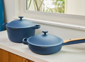Two blue cookware items on a kitchen counter with a window in the background